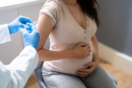 Doctor giving Covid-19 Vaccine Injection To Pregnant Woman Patient.