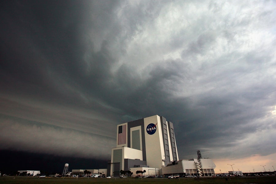 Wide angle photograph of the NASA Vehicle Assembly Building in Cape Canaveral, Florida with a thunderstorm looming overhead