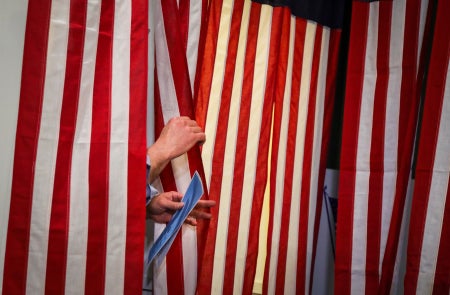 A voter prepares to leave a voting booth with American flag curtains