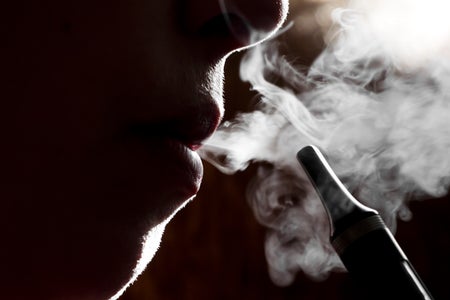 Silhouette of a person vaping electronic cigarette, close up.